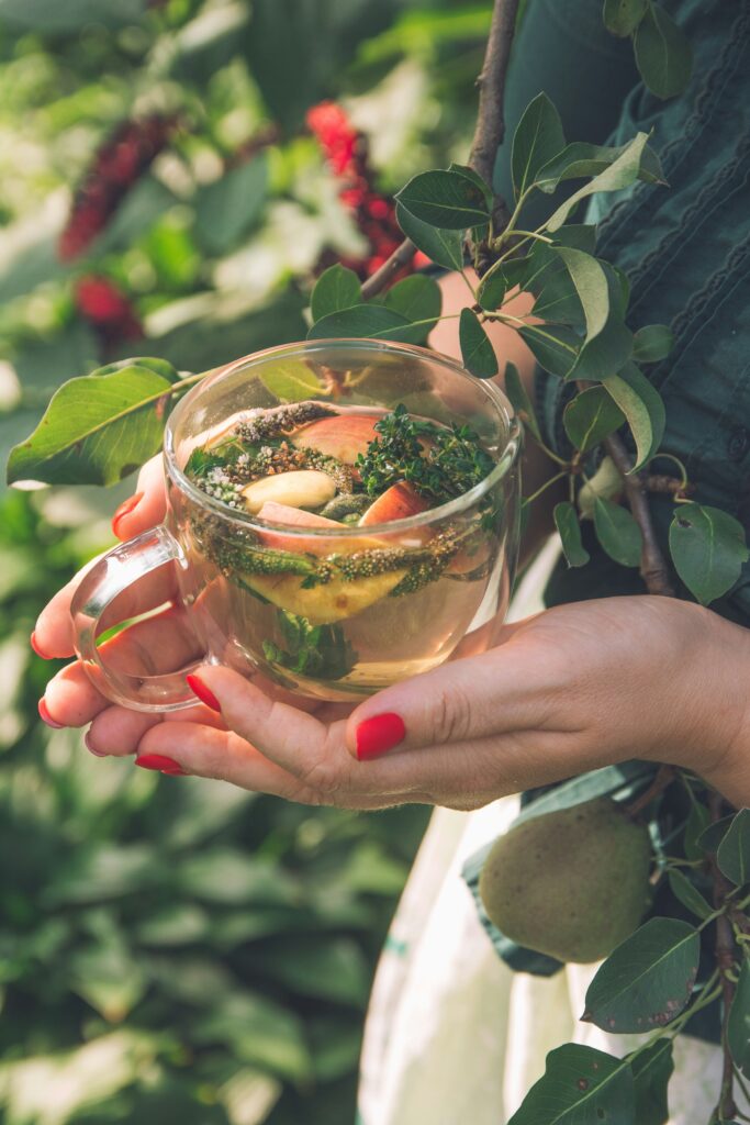 woman holding herbal tea in glass mug
